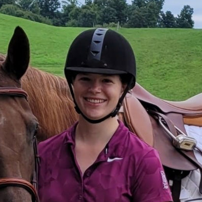 Ashley Hayes in helmet, standing next to her horse