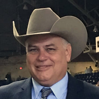 Dewey Smith headshot wit cowboy hat and suit